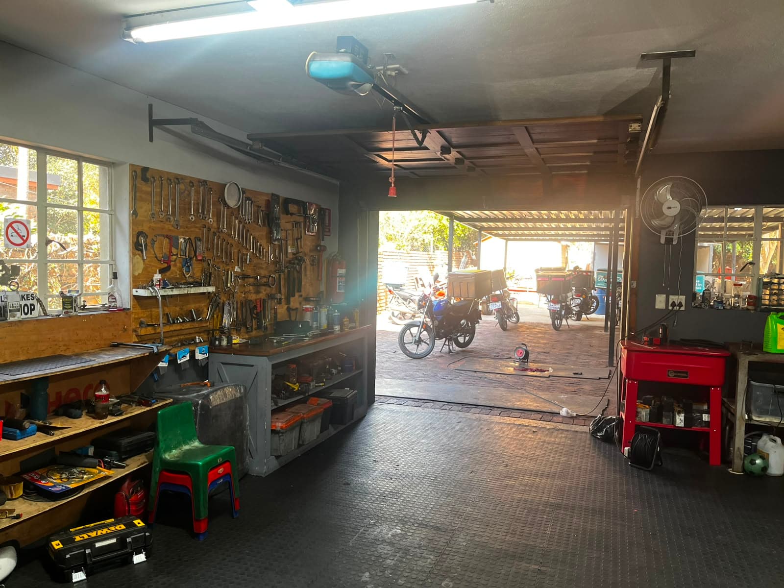 Workshop bench and tool wall, with bikes in the yard beyond
